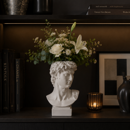 Weiße Vase in Form der Büste von David mit Blumen in einem Regal