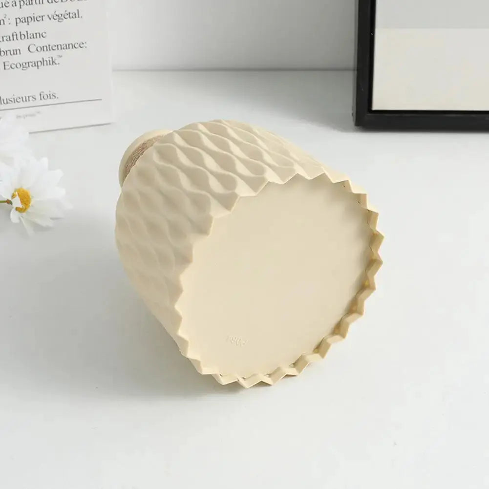 Eine Vase aus Kunststoff in Beige liegt auf dem Tisch