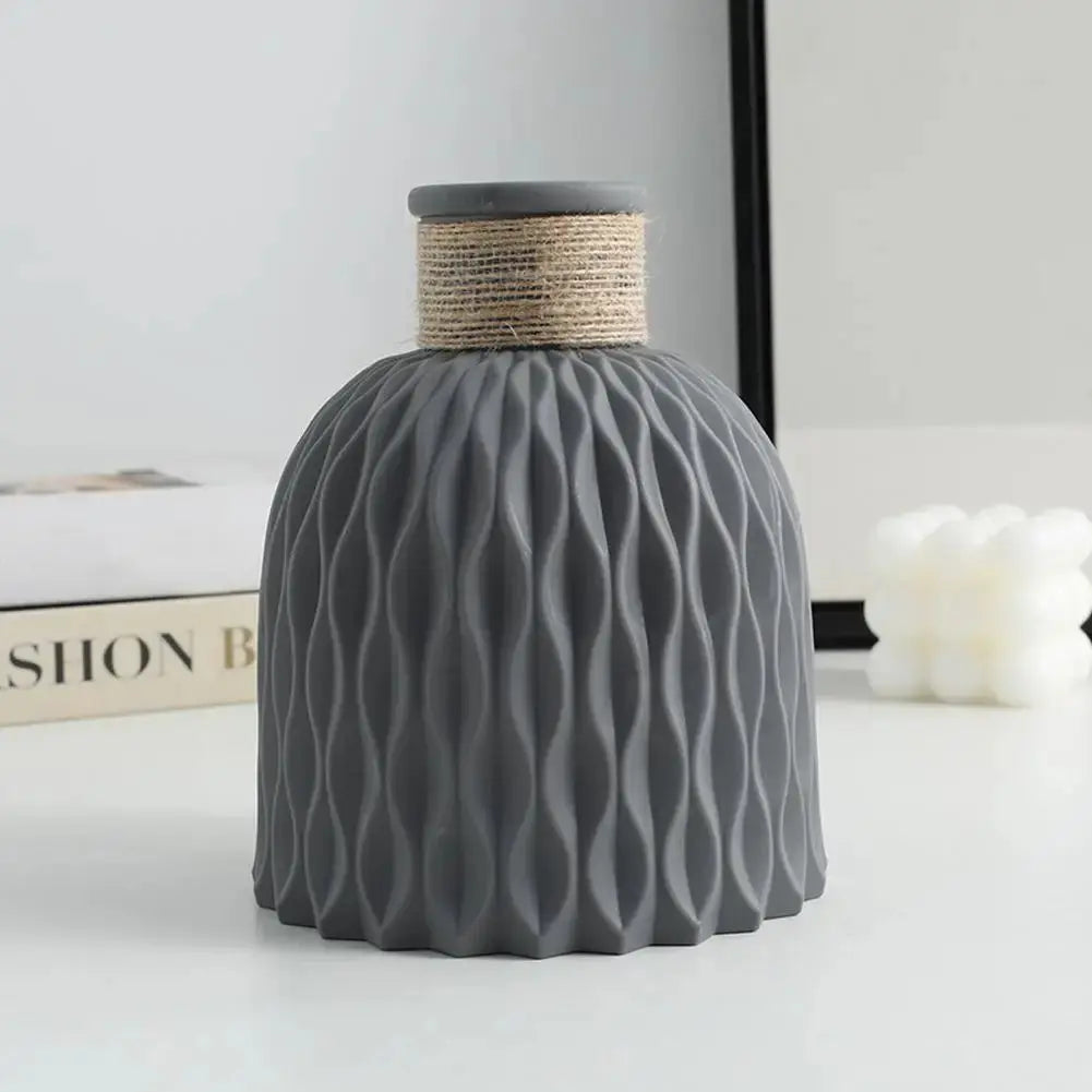 Eine Vase aus Kunststoff in Grau steht auf einem Tisch
